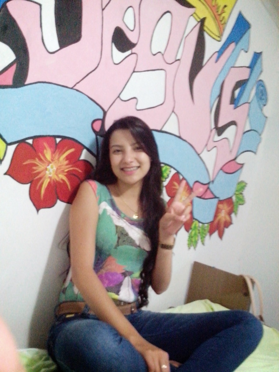 Young Maysa Tavares smiling in front of a colorful painted mural